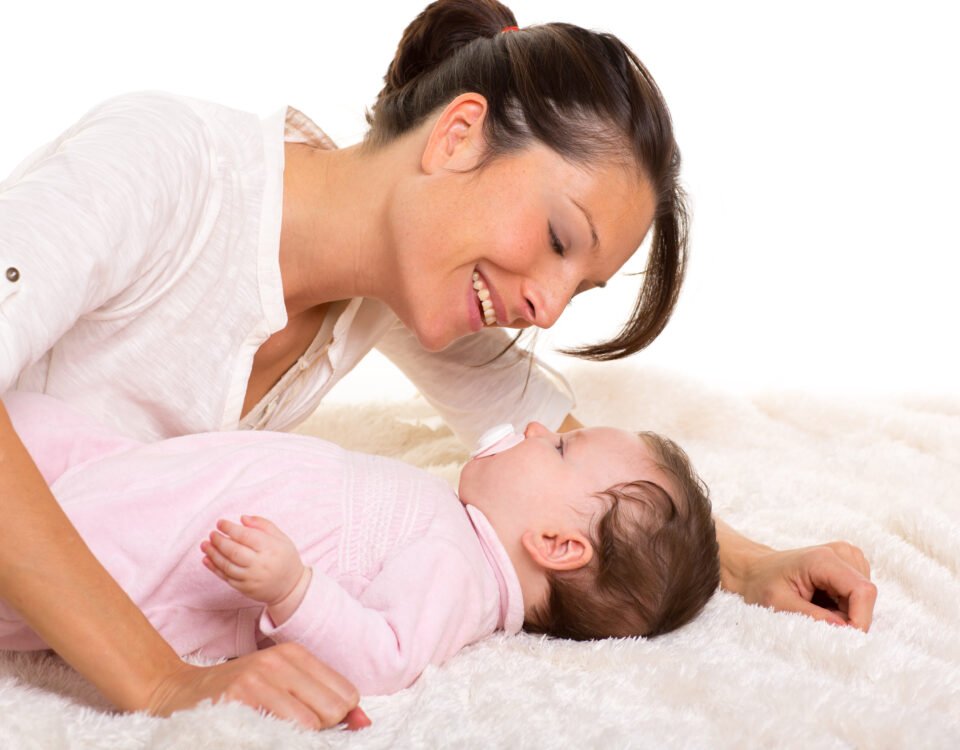 Baby girl and mother lying happy playing together